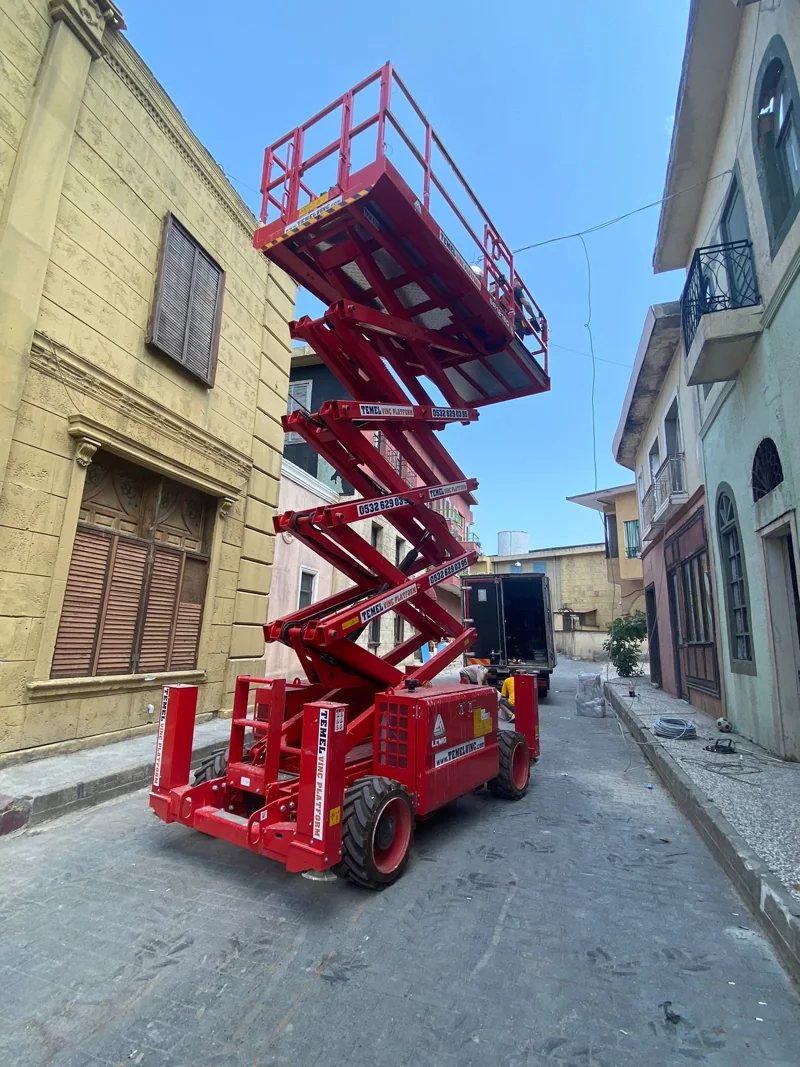 Binalar arasında yükseltilmiş kırmızı makaslı platform